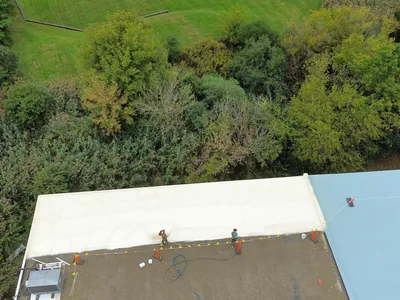 Roof coating being sprayed onto a commercial roof by the Meadow Springs crew
