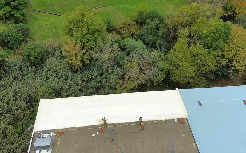 Roof coating being sprayed onto a commercial roof by the Meadow Springs crew
