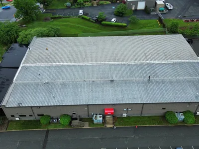 Weathered commercial metal roof showing rust and fastener failure