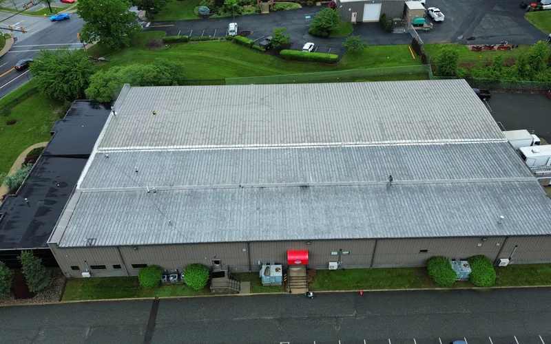 Weathered commercial metal roof showing rust and fastener failure